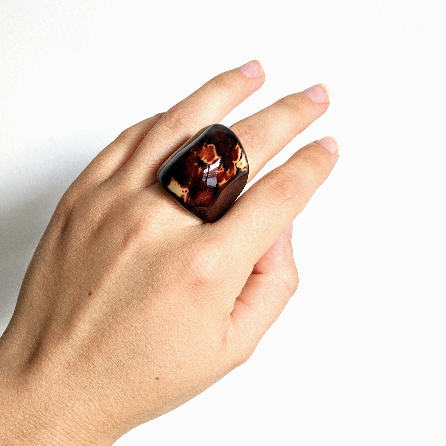 Hand wearing brown handmade ring stone on a white background