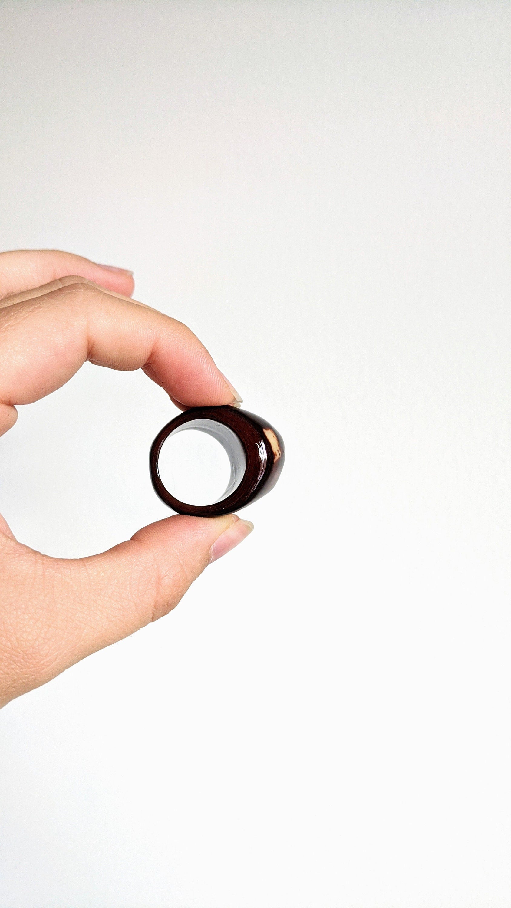 Hand holding a tagua nut ring against a white background