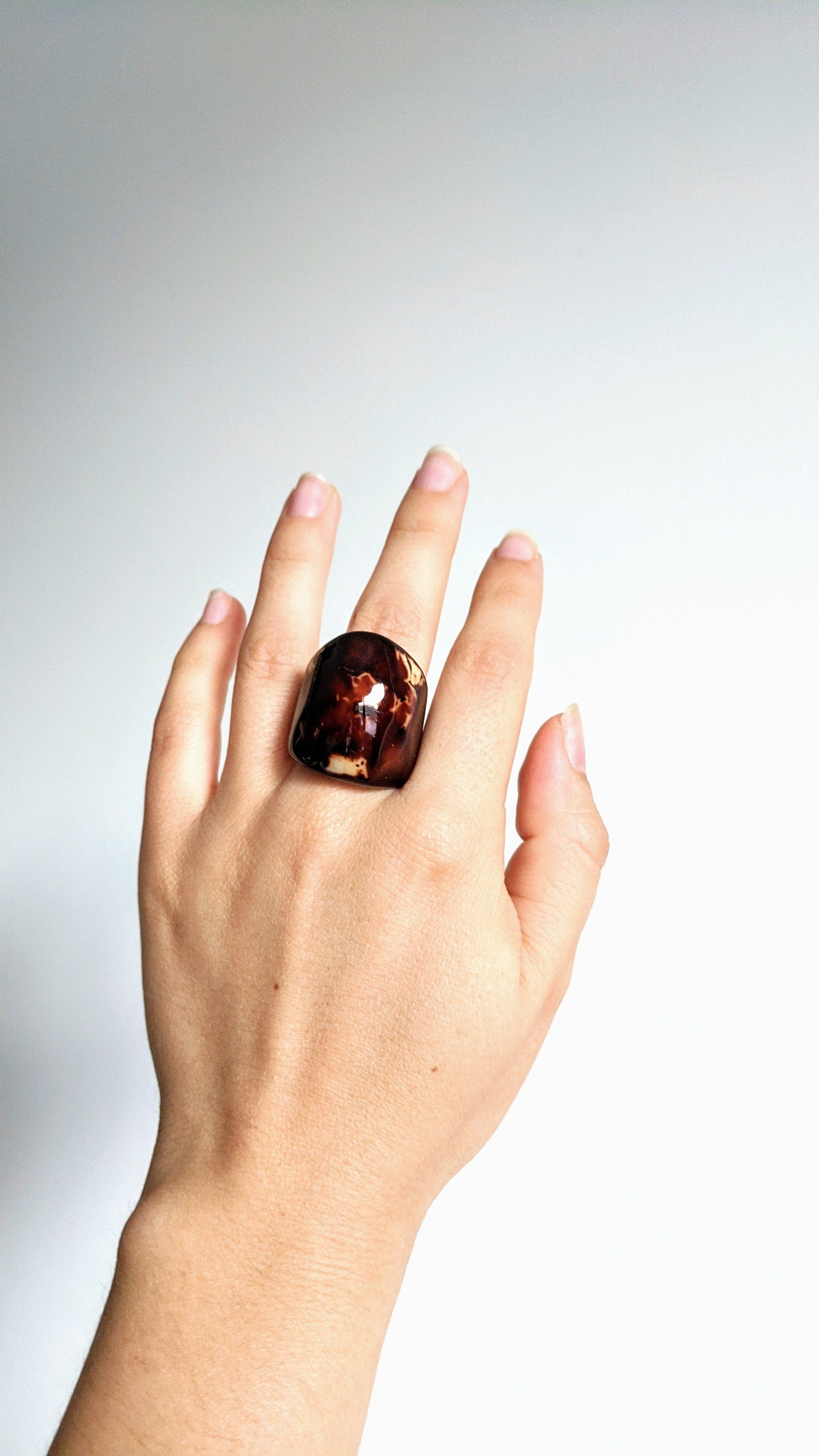 Hand wearing a large ring on a plain background