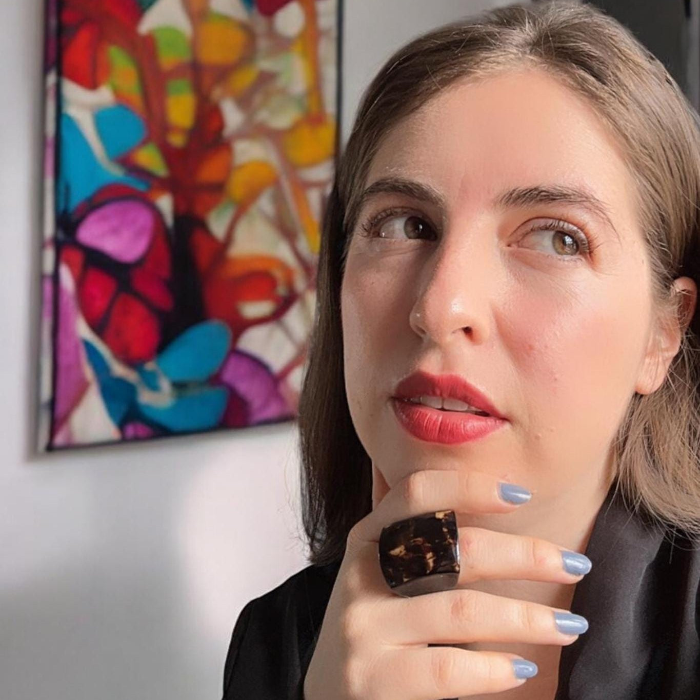 Woman with red lipstick and a colorful abstract painting in the background