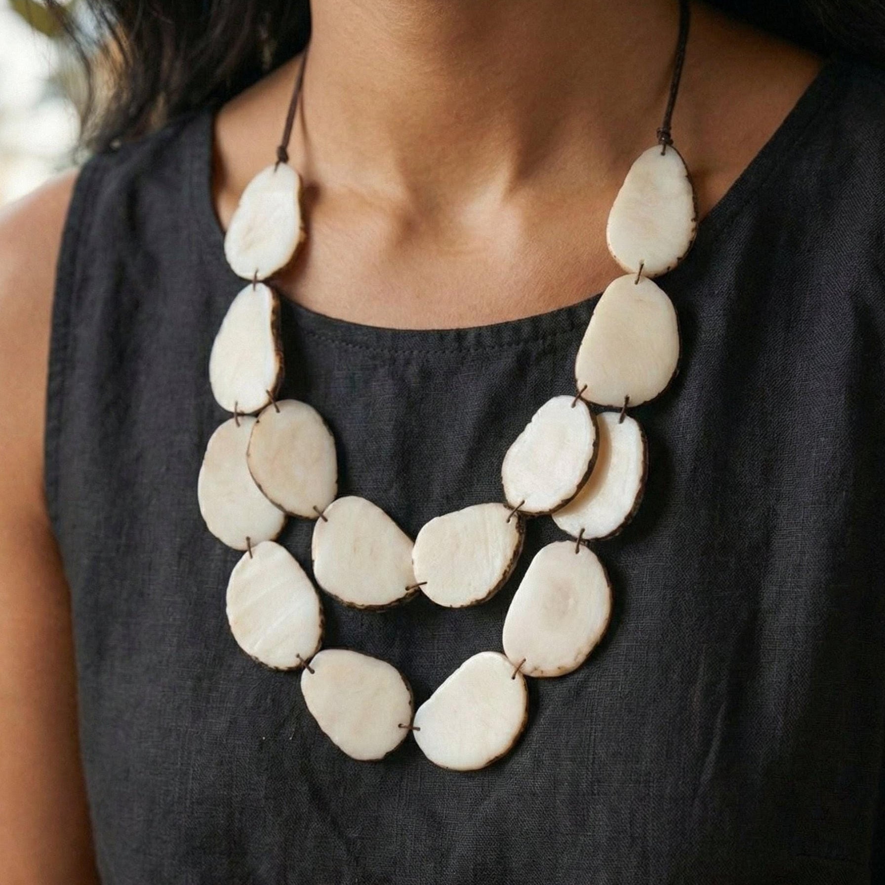 Necklace with large white beads worn by a person in a black top.